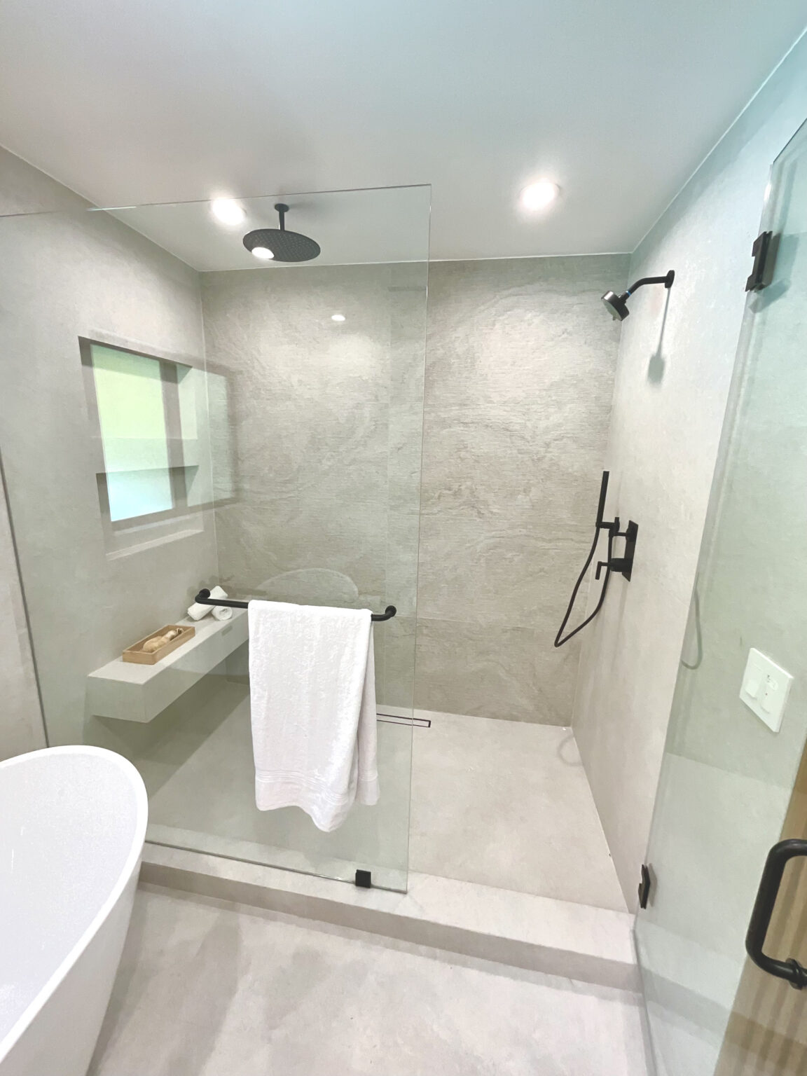 Remodeled walk-in shower with gray tile and glass enclosure