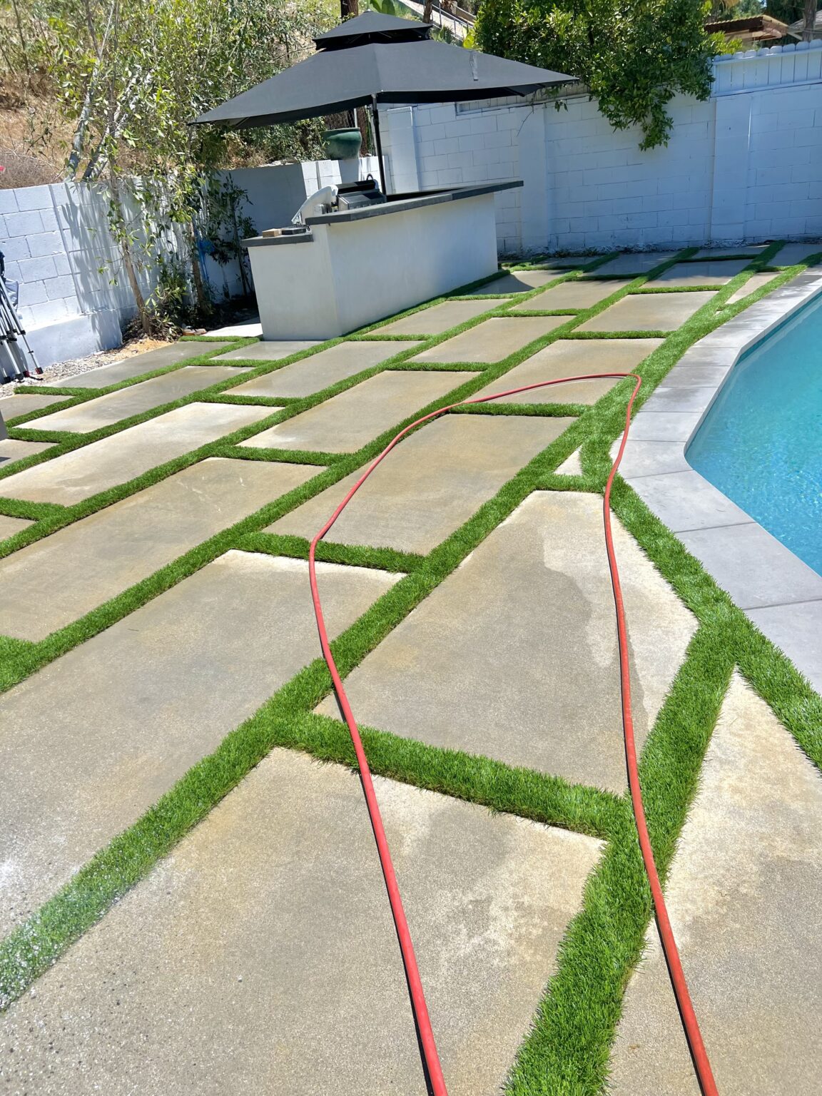 New concrete pavers and turf beside a backyard pool